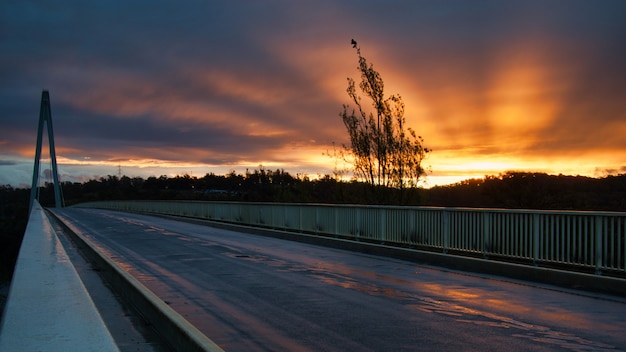 Foto escénica de una puesta de sol desde un puente con hermosos rayos que irradian del sol