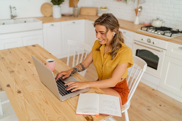 Foto de estilo de vida interior de ama de casa feliz buscando algunos recibos y bebiendo café en una cocina moderna y ligera