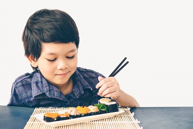 Foto de estilo vintage de niño encantador asiático está comiendo sushi