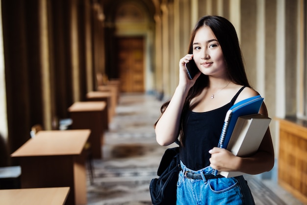 Una foto de un estudiante asiático hablando por teléfono en la universidad