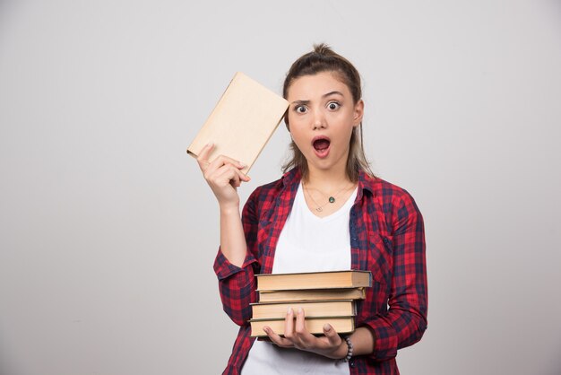 Foto de un estudiante sorprendido sosteniendo una pila de libros.