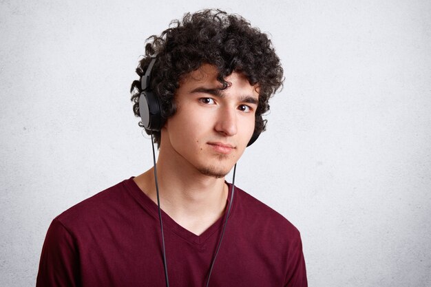 Foto de estudio de adolescente masculino escucha música en auriculares modernos