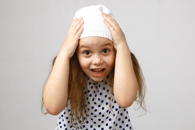 Foto de estudio de adorable linda niña preescolar expresando conmoción y asombro