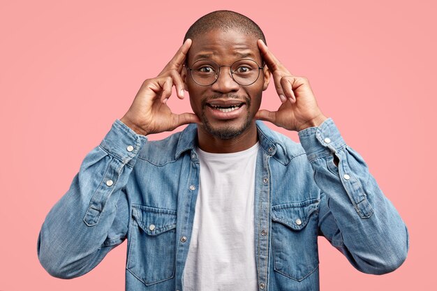 Foto de estudio de alegre joven negro mantiene los dedos índices en las sienes