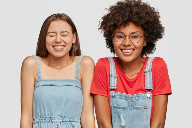 Foto de estudio de alegres mujeres de raza mixta se ríen alegremente de buen chiste