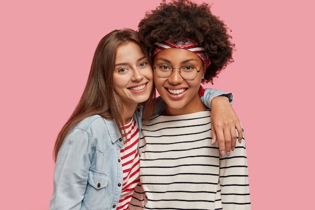 Foto de estudio de bonitas dos jóvenes mujeres de raza mixta felices están muy cerca una de la otra