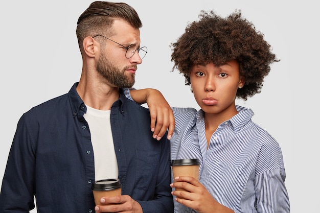 Foto de estudio de desconcertado pareja interracial tienen coffee break