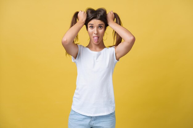 Foto de estudio de una encantadora chica caucásica aislada en un fondo amarillo Retrato interior de una bella dama jugando con su cabello oscuro con una sonrisa suave y juguetona