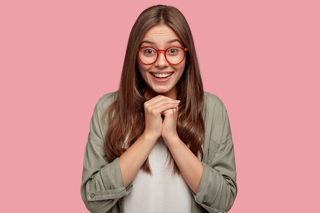 Foto de estudio de estudiante satisfecho posando contra la pared rosa