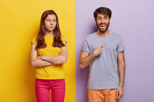 Foto de estudio de la feliz pareja milenaria posando contra la pared de dos colores