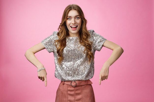 Foto de estudio impresionado emocionado atractivo joven moda mujer caída mandíbula emocionado apuntando hacia abajo ind ...