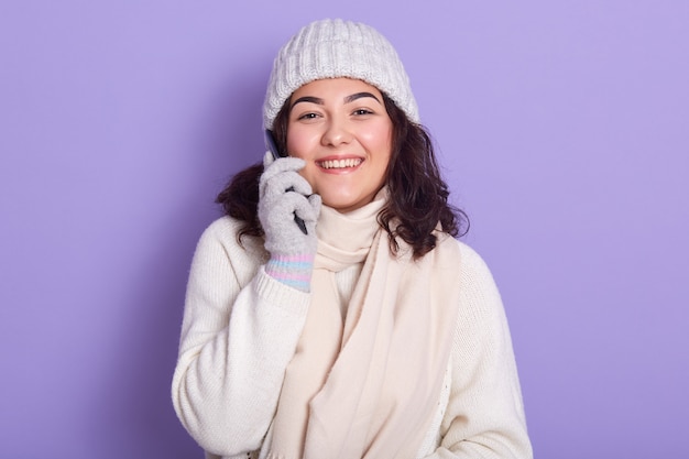 Foto de estudio interior de positivo joven modelo sonriente de pie aislado sobre lila