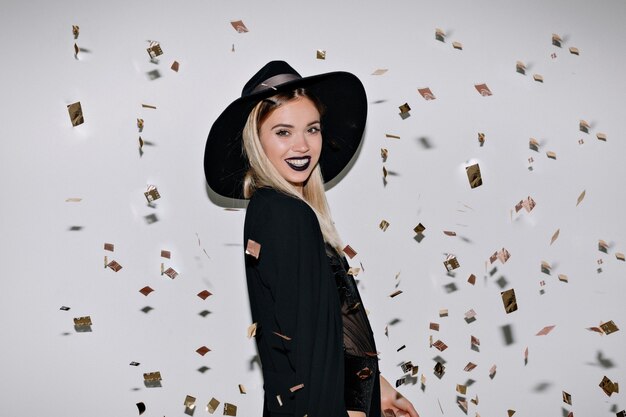 Foto de estudio en interiores de increíble modelo femenino en traje negro sonriendo