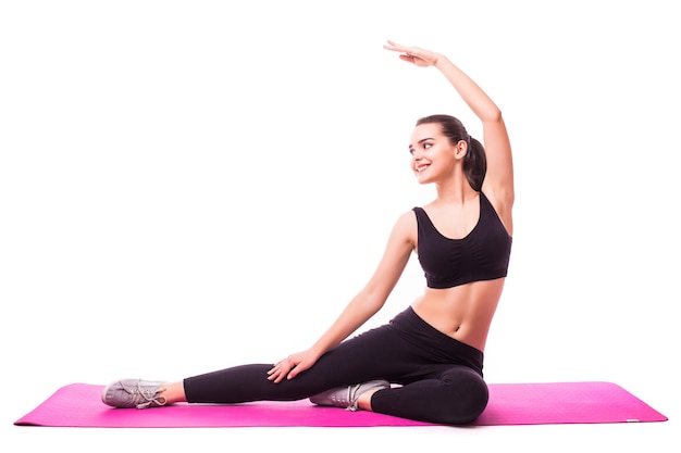 Foto de estudio de una joven mujer en forma haciendo ejercicios de yoga aislado sobre fondo blanco.