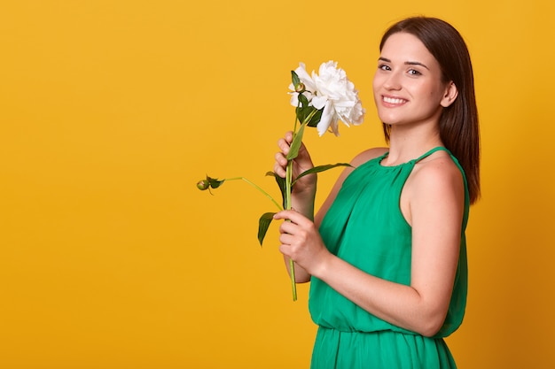 Foto de estudio de mujer encantadora con elegante vestido verde aislado sobre amarillo