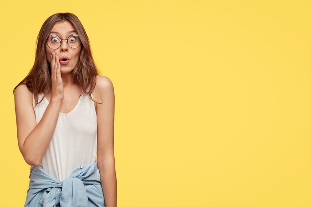 Foto de estudio de mujer europea emocional estupefacta expresa asombro