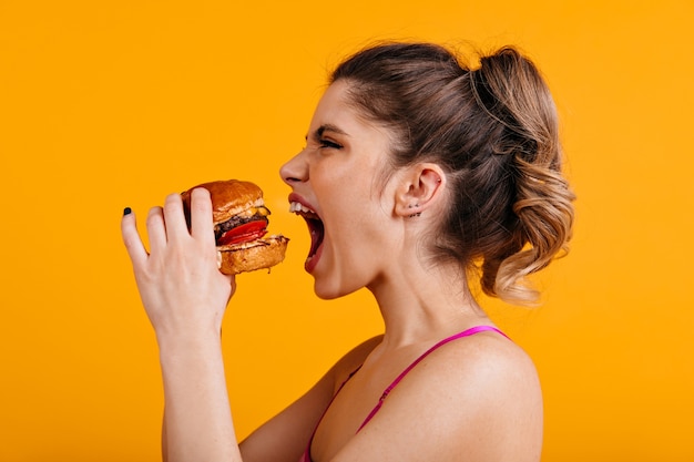 Foto de estudio de mujer hambrienta con sandwich