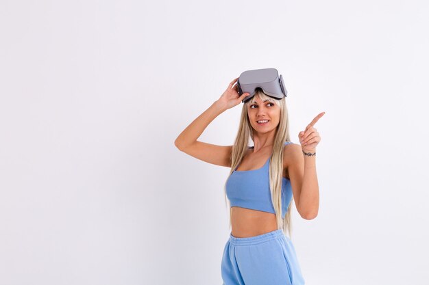 Foto de estudio de una mujer joven y atractiva en un traje de moda azul cálido con gafas de realidad virtual sobre un fondo blanco