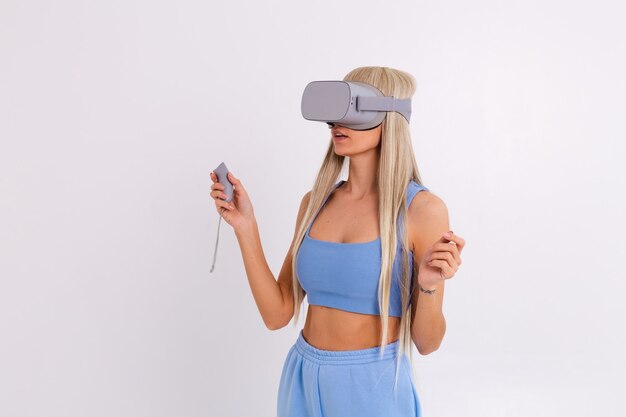 Foto de estudio de una mujer joven y atractiva en un traje de moda azul cálido con gafas de realidad virtual sobre un fondo blanco