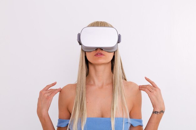 Foto de estudio de una mujer joven y atractiva en un traje de moda azul cálido con gafas de realidad virtual sobre un fondo blanco
