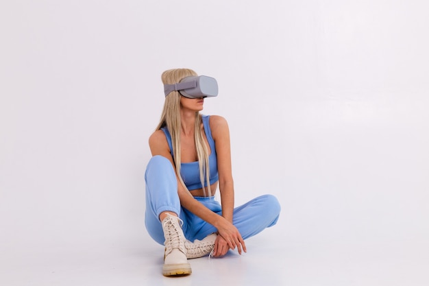 Foto de estudio de una mujer joven y atractiva en un traje de moda azul cálido con gafas de realidad virtual