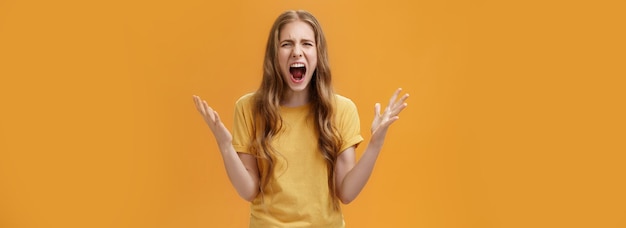 Foto gratuita foto de estudio de mujer joven durante la discusión perdiendo los estribos de pie presionado y cabreado gritando l