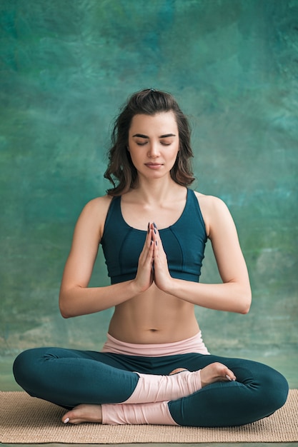 Foto de estudio de una mujer joven en forma haciendo ejercicios de yoga en el espacio verde