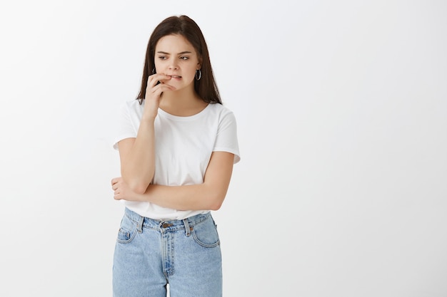 Foto gratuita foto de estudio de una mujer joven con problemas posando contra la pared blanca