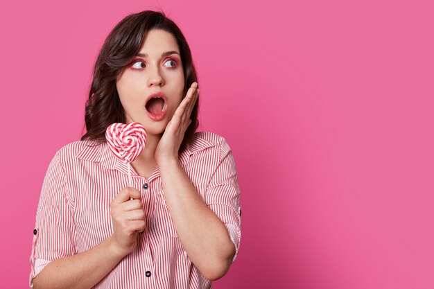 Foto de estudio de mujer sorprendida sorprendida con cabello oscuro