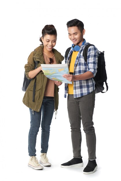 Foto de estudio de una pareja joven con mochilas navegando por el mapa contra el fondo blanco.