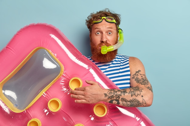 Foto de estudio de sorprendido hombre rojo barbudo lleva máscara de snorkel