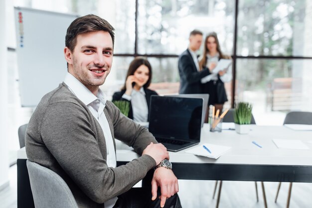 Foto de exitoso hombre de negocios guapo con su equipo trabajando en la oficina.