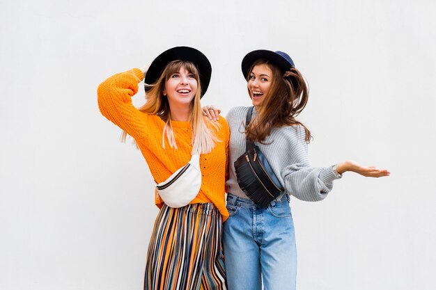 Foto exterior de dos amigas alegres pasar un buen rato juntos posando en blanco