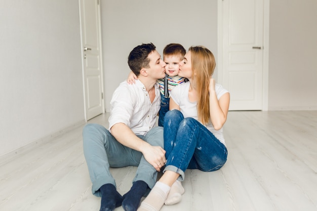 Foto de familia de dos padres jóvenes jugando con su hijo