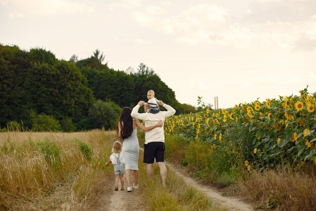 Foto de familia feliz. Padres e hija. Familia junta en campo de girasol. Hombre con camisa blanca.