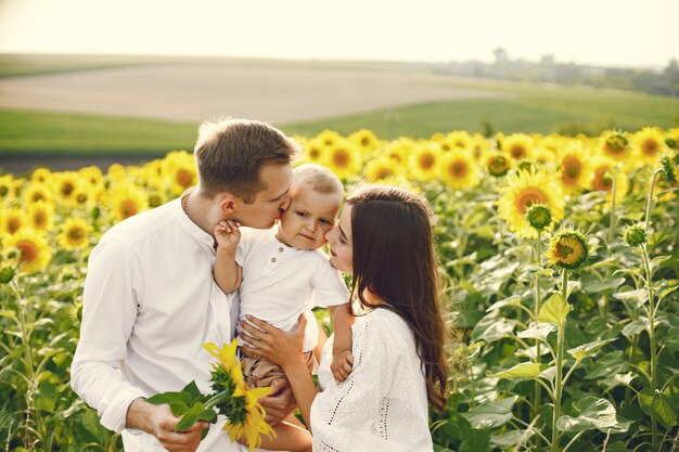 Foto de una familia joven en el campo de girasoles en un día soleado.