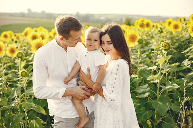 Foto de una familia joven en el campo de girasoles en un día soleado.