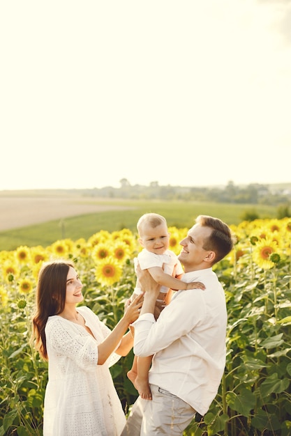 Foto de una familia joven en el campo de girasoles en un día soleado.