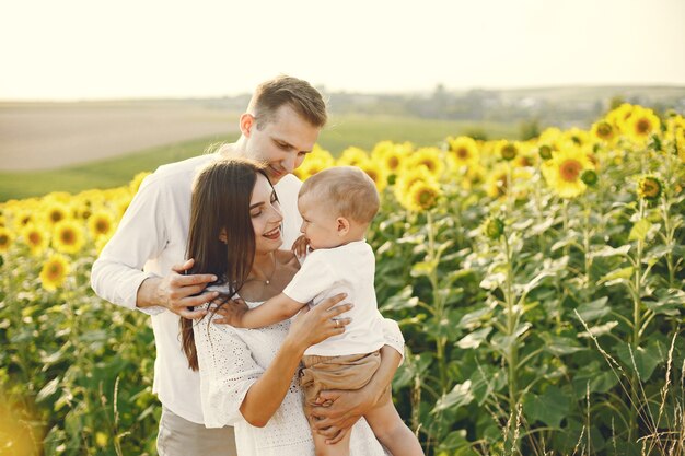 Foto de una familia joven en el campo de girasoles en un día soleado.