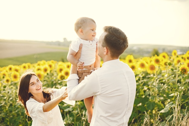 Foto de una familia joven en el campo de girasoles en un día soleado.