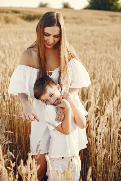 Foto de una familia joven de pie en el campo de trigo en un día soleado.