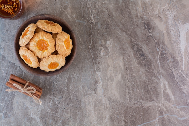 Foto de gran angular de galletas de mermelada caseras en un cuenco de madera sobre gris.