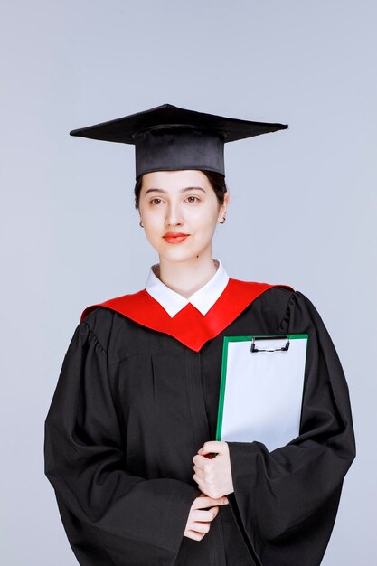 Foto de hermosa estudiante de posgrado con portapapeles posando. Foto de alta calidad