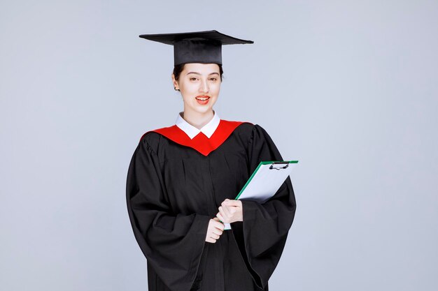 Foto de hermosa estudiante de posgrado con portapapeles posando. Foto de alta calidad