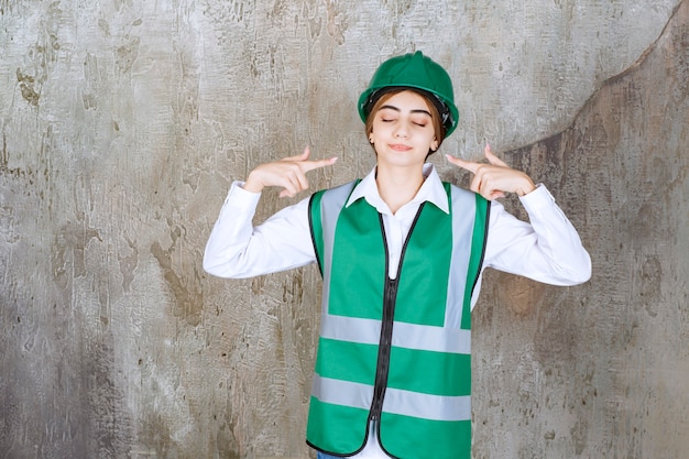 Foto de hermosa mujer arquitecto en casco verde apuntando