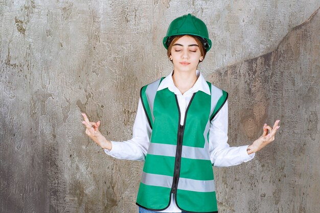 Foto de hermosa mujer arquitecto en casco verde de pie sobre mármol