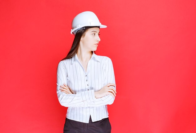 Foto de una hermosa mujer de negocios con sombrero de seguridad de pie con los brazos cruzados.