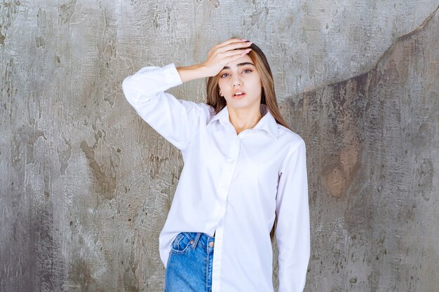 Foto de hermosa mujer de pelo largo en blusa blanca con dolor de cabeza