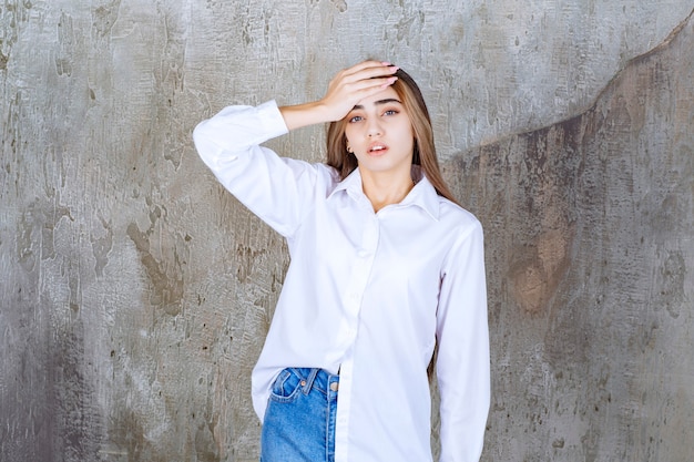 Foto de hermosa mujer de pelo largo en blusa blanca con dolor de cabeza