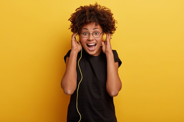 Foto de hermosa mujer de piel oscura con peinado afro se inspira en la música, elige una buena pista